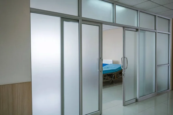Interior of hospital with open door and patient bed in ward