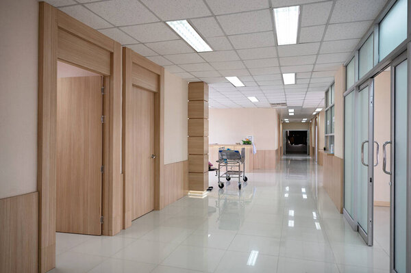 Interior of empty hospital corridor with various rooms and trolley patient service at reception