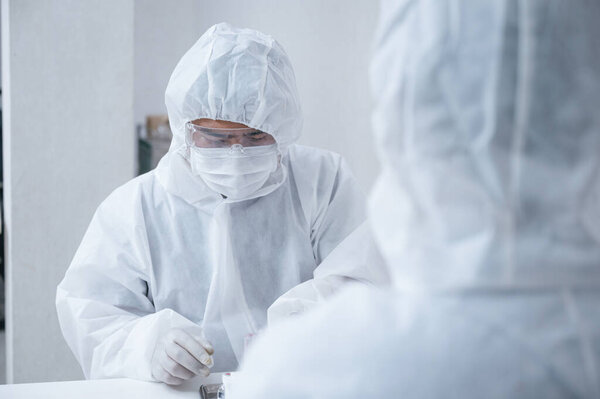 Команда химиков в защитном костюме изобретает и исследует антивирусный препарат Ковид-19, коронавирус в лаборатории