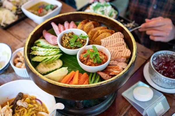 Set appetizer of Northern Thai Food with fried pork, sausage, vegetables and thai chili sauce dip on Khantoke or traditional container in restaurant