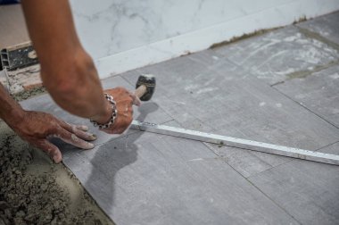 Yerde yatan bir el ve yere granit döşeyen bir çekiç kullan.