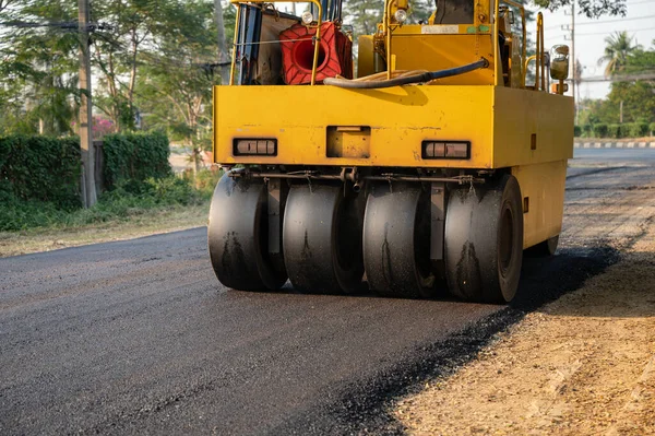 Heavy vibration yellow steamroller or soil compactor working on hot-mix asphalt pavement road at construction site