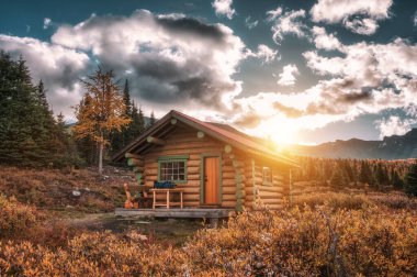 Sunrise on wooden hut in autumn forest at Assiniboine provincial park, Canada clipart