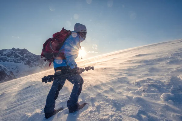 ノルウェーの吹雪の中で太陽と雪の山に登山バックパッカーの男 — ストック写真