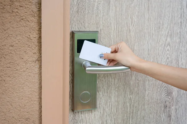 Hand holding key card scanning to unlock wooden door at resort. Digital door scanner access control security system