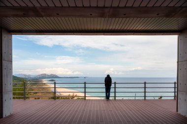 Ahşap balkondaki sınır denizi manzarasına bakan adamın arkası. 