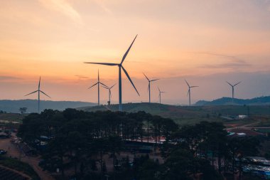 Alternatif enerji türbinleri. Akşamları tarım alanlarında tepenin üzerinde temiz ve yenilenebilir enerji.