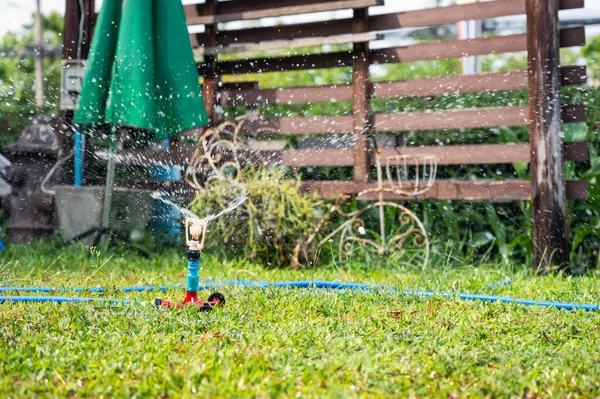 裏庭の緑の芝生に散水自動ウォータースプリンクラーシステム — ストック写真