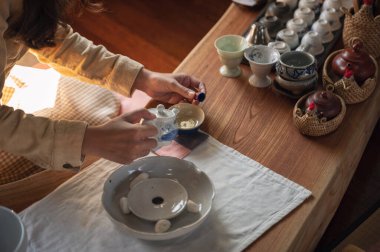 Kadın elleri çaydanlıktan çay dolduruyor tahtadan bir fincanda