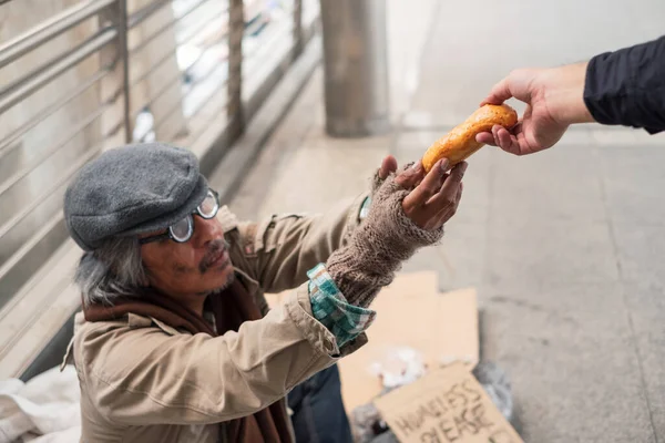 在走廊桥上 无家可归的乞丐伸手到捐款者手里拿面包 — 图库照片