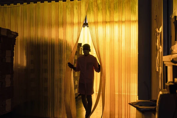加工饮料厂的非洲男性工人打开塑料窗帘进入纸板包装仓库 — 图库照片