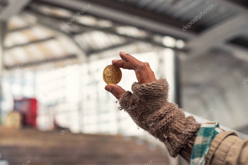 Dirty hand homeless holding gold coin of cryptocurrency 