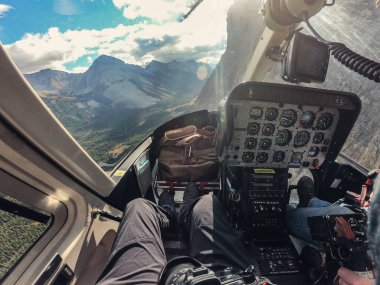 Kokpitin içinde ulusal parktaki Rocky dağlarının üzerinden uçan bir helikopter var. POV Vuruşu