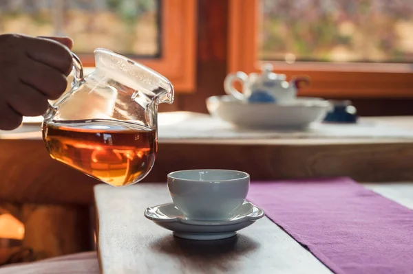 Tahta Masada Çay Fincanındaki Cam Sürahisinden Sıcak Çay Dökülüyor — Stok fotoğraf
