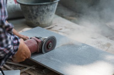 İnşaat alanında granit karo kesen elektrikli testere kullanan bir işçi.