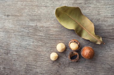 Ahşap masadaki yapraklı organik Macadamia fındıkları.