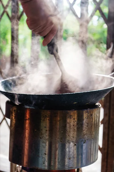 Tayland mutfağında geleneksel metal ocağın üstünde sıcak tavada kızaran bir spatulayla el ele tutuşmak.