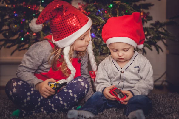 Irmão e irmã debaixo da árvore de Natal — Fotografia de Stock