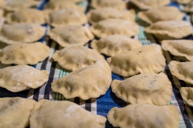 İtalyan mantısına benzer geleneksel Polonya yemekleri, hamur içinde taze sarılmış ve mutfak masasında kurutulmaya hazır.