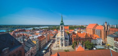 Torun, Polonya - Ağustos 2020: Kutsal Ruh Kilisesi 'nin güneş ışığı altındaki binalar ve Polonya' nın eski Torun kentinde mavi bir gökyüzü altında panoramik görünümü
