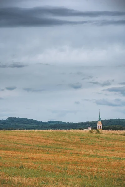 Ένα Αγροτικό Πεδίο Κάτω Από Συννεφιασμένο Ουρανό Και Πύργο Εκκλησία — Φωτογραφία Αρχείου