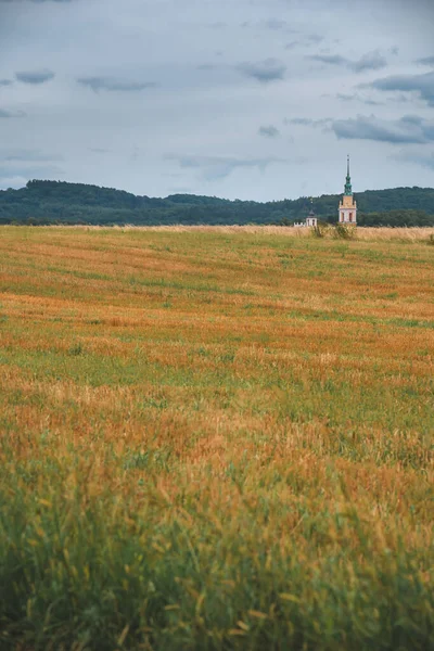 Ένα Αγροτικό Πεδίο Κάτω Από Συννεφιασμένο Ουρανό Και Πύργο Εκκλησία — Φωτογραφία Αρχείου