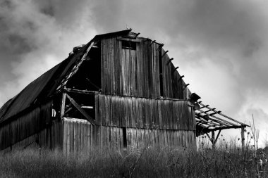 Kuzey Carolina 'daki kırsal ahır üzerinde fırtına bulutları uçuşuyor. Görüntü siyah beyaz.