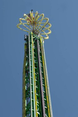 Bayrak, neon ışıklarla aydınlatılmış uzun bir lunapark gezisinin tepesinde. Mavi gökyüzü çizgileri geziniyor.