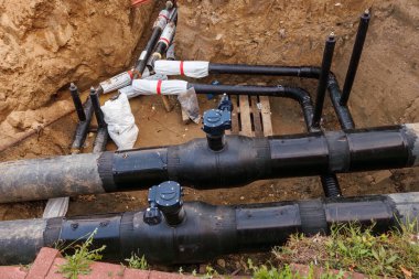 Geniş çaplı plastik su boruları ve körfez vanaları olan bir tamir çukuru. Küçük çaplı priz boruları. Borular görüntünün yanında..