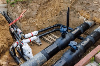 Geniş çaplı plastik su tedarik boruları olan bir onarım çukuru, giriş vanalarıyla birlikte. Bir açıda küçük çaplı çıkış boruları.