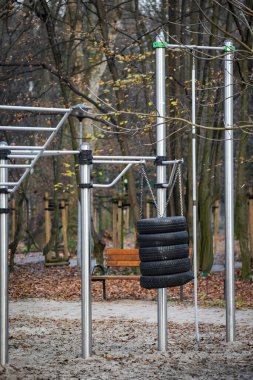 Paslanmaz çelik yatay parmaklıkları ve yumruk pratiği için askıya alınmış lastikleri olan bir çocuk parkı. Açık hava spor malzemeleri. Sağlıklı yaşam tarzı.