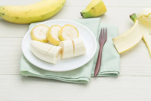 Geschnittene Banane auf Schüssel auf weißem Holztisch — Stockfoto