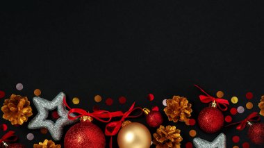 Noel ve Yeni Yıl kompozisyonu. Noel kırmızısı ve altın cam süsleme topu siyah arka planda parıltılı serpiştirilmiş. Düz katman, üst görünüm, boşluğu kopyala