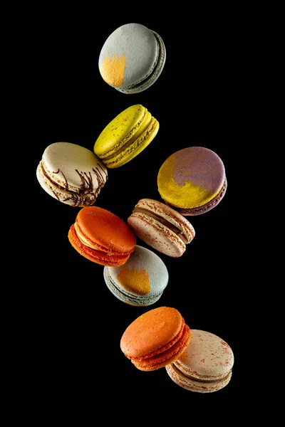 Siyah zemin üzerinde izole edilmiş uçan renkli badem kurabiyeleri ya da pastalar havada asılı duruyor. Tatlı ve renkli tatlı Kopya Uzay Renkli Fransız kurabiyeleri