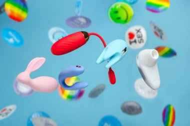 Bright colorful concept for sex shop. Vaginal balls, dildo for the clitoris, We-Vibe and Womanizer on a background of rain out of condoms. Festive image of sex toys, gadgets, masturbation device.