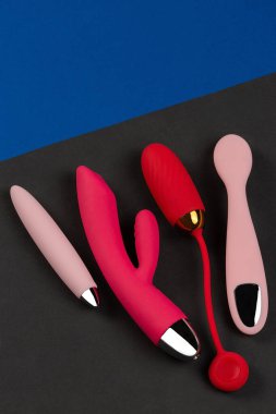 Siyah ve mavi arka planda çok renkli seks oyuncakları. Erotik zevk oyuncağı. Seks aleti ve mastürbasyon aleti. Üst Manzara. Mesaj için yer. Düz yatıyordu. Vibratör, vibratör, vibratör...