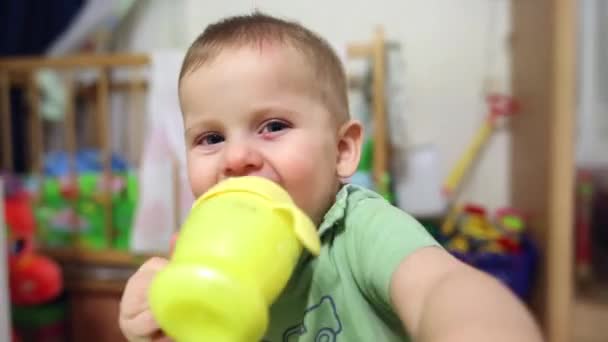 El niño está bebiendo de un tazón para beber y de una mano que cubre la lente — Vídeo de stock