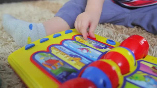 Палец ребенка нажимает кнопку на музыкальной игрушке — стоковое видео