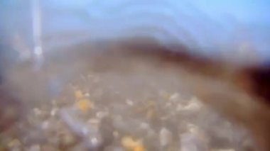 Küçük çakıl taşları ve deniz sörf ile çakıl plajı. Bir vahşi çakıl plajı deniz yüzeyi. Dalgalar için kamera vardır. Görünüm su altında. Dalga köpüğü.