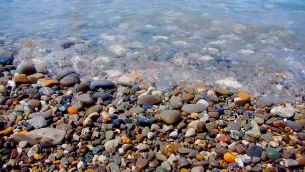 Playa de guijarros con guijarros pequeños y surf de mar. La superficie del mar en una playa de guijarros silvestres. Las olas son para la cámara. La vista bajo el agua. Espuma de onda . — Vídeos de Stock