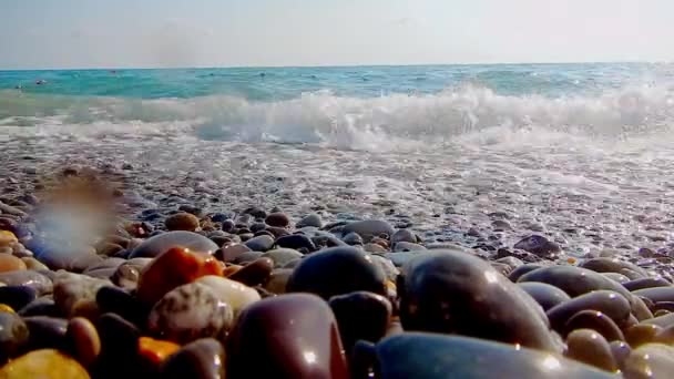 Playa de guijarros con guijarros pequeños y surf de mar. La superficie del mar en una playa de guijarros silvestres. Las olas son para la cámara. La vista bajo el agua. Espuma de onda . — Vídeo de stock