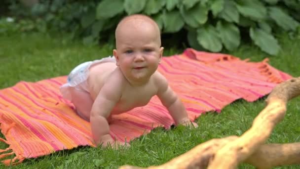 Das Kind lernt auf dem Teppich zu kriechen, auf dem Gras, lächelnd — Stockvideo