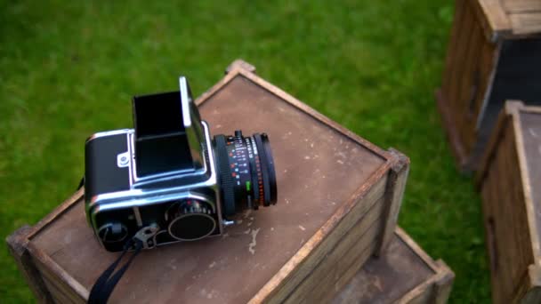 Камера Hasselblad лежит на деревянной коробке на заднем плане травы — стоковое видео