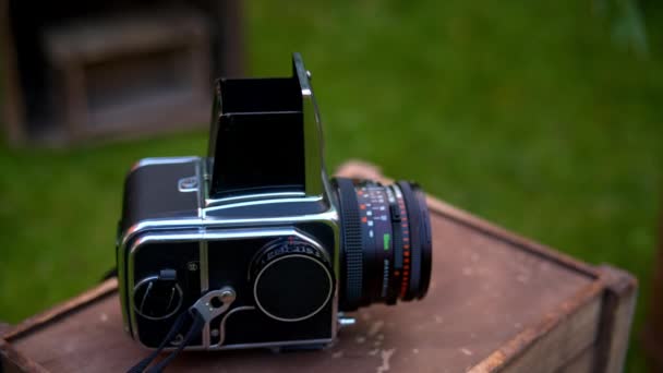 Camera Hasselblad lies on a wooden box on a grass background — Stock Video