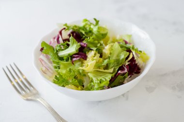 Karışık taze sebze salatası (yeşil marul, radicchio ve frisee) beyaz bir arka plan üzerinde beyaz kase