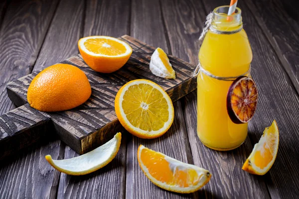 Composition avec bouteille de jus d'orange et fruits sur fond de bois brun. Concentration sélective . — Photo