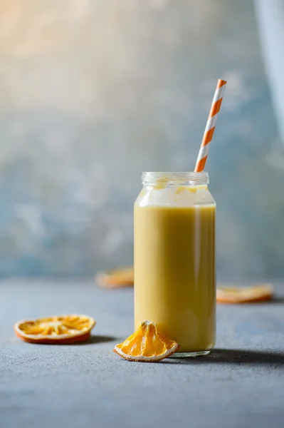 Smoothie aux fruits orange sain dans un bocal en verre sur fond bleu avec des oranges séchées — Photo