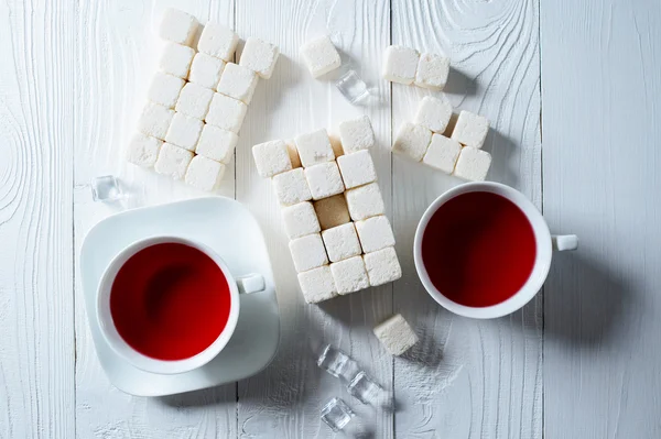 Bir fincan çay ile beyaz bir arka plan üzerinde beyaz şeker parçaları kuleden — Stok fotoğraf