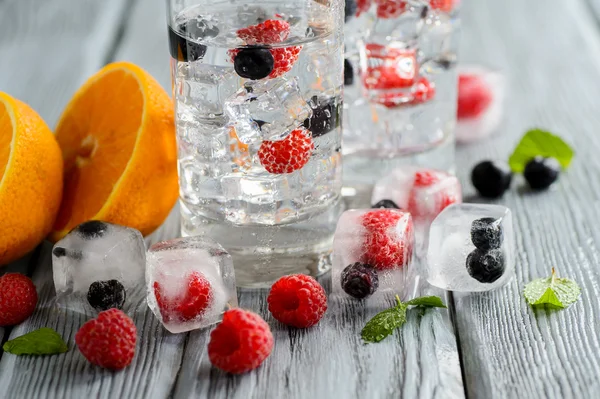 Холодний коктейль з лісовими ягодами, заморожений у кубиках льоду на дерев'яному столі — стокове фото