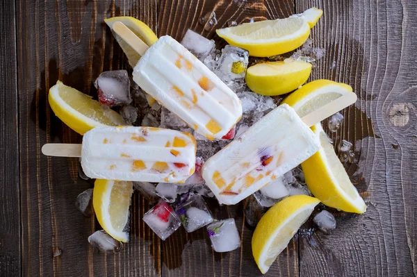 Refrescante picolé de frutas no fundo do gelo com pedaços de limão e maçã — Fotografia de Stock